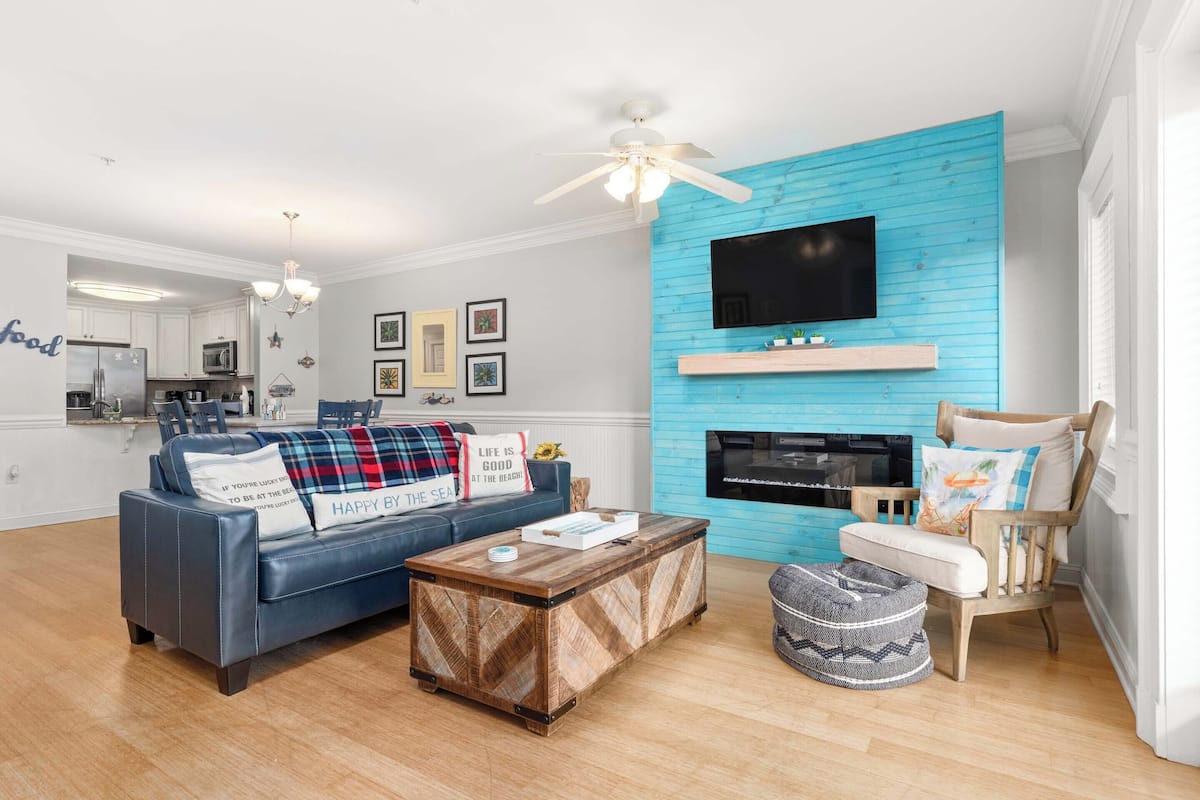 A living room with a blue accent wall, a fireplace, a television, a sofa, and a coffee table.