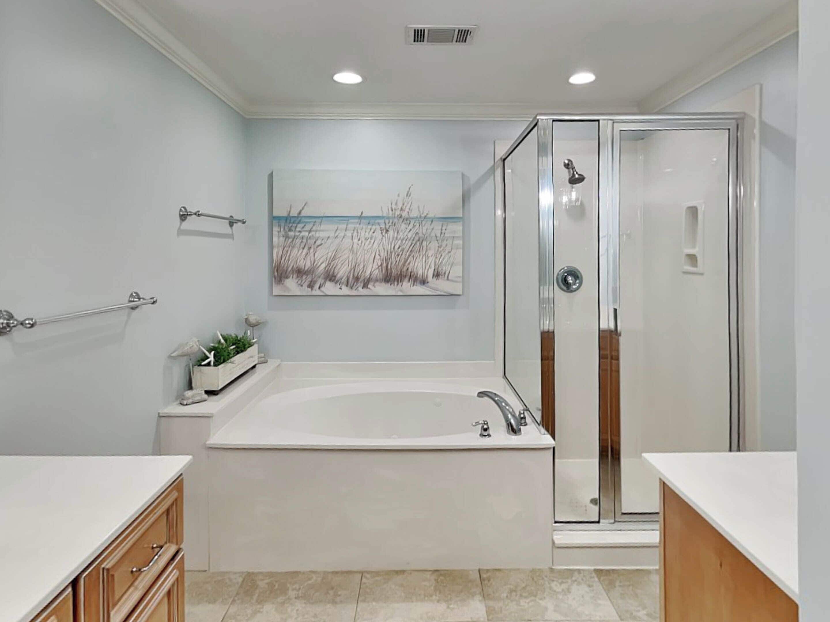 A modern bathroom with a large bathtub, a glass-enclosed shower, and a wall-mounted towel rack.