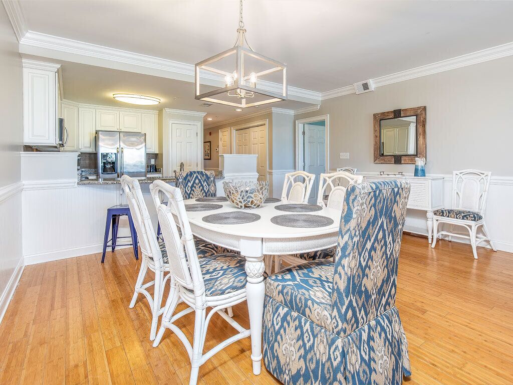 A dining area with a round table, white chairs, and patterned upholstery.