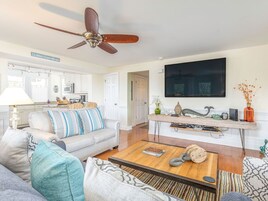 A living room with a sofa, coffee table, and a TV mounted on the wall.