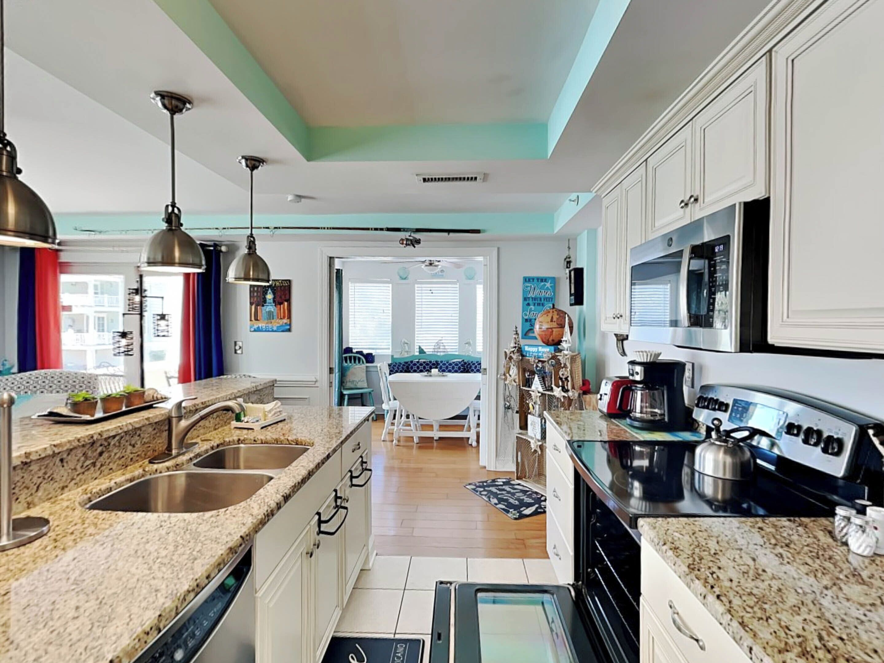 A modern kitchen with granite countertops, stainless steel appliances, and a view to the living area.