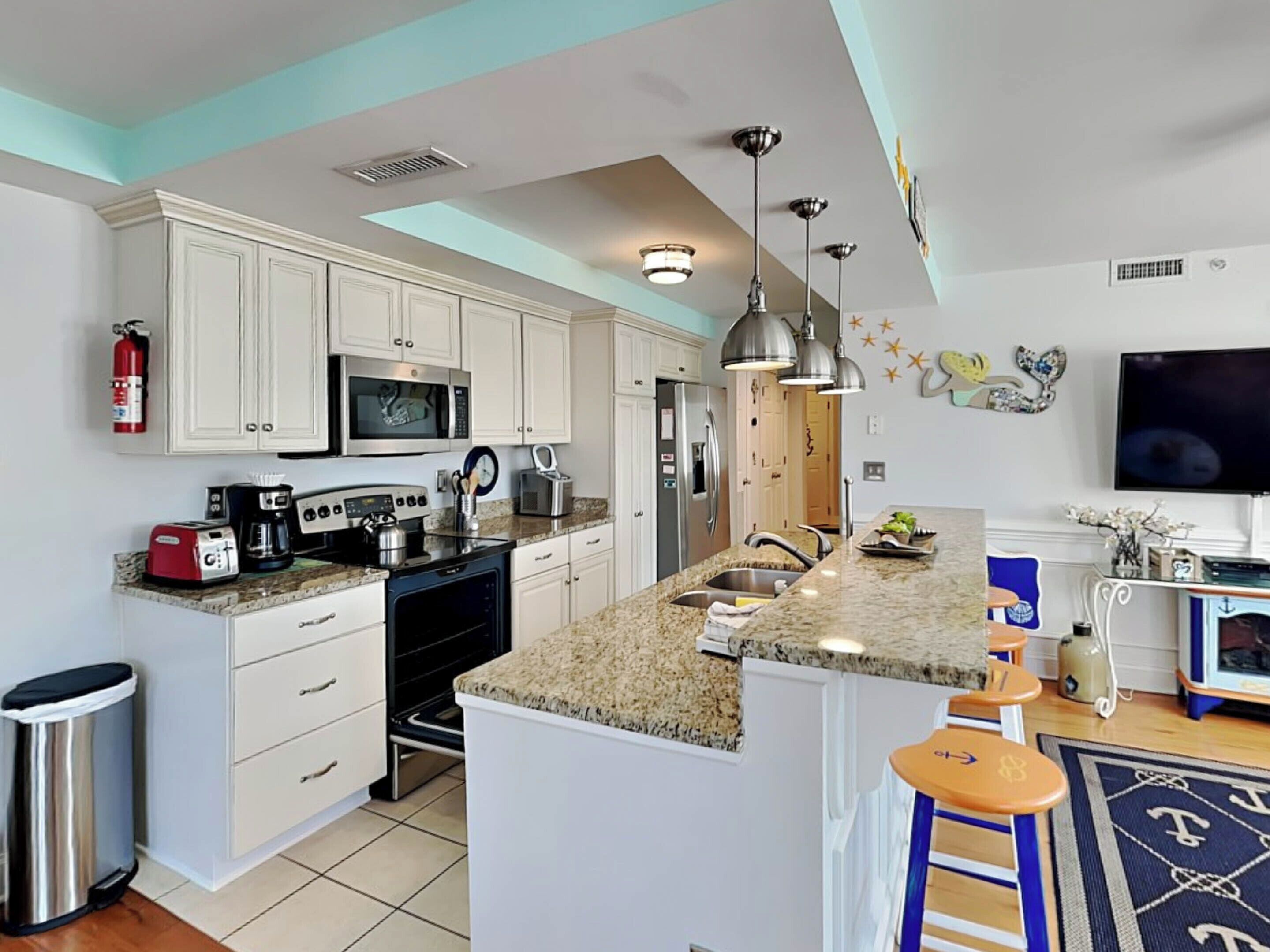 A modern kitchen with white cabinets, a granite countertop, stainless steel appliances, and a bar area with stools.