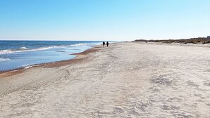 Ein weiter Sandstrand unter blauem, klarem Himmel.