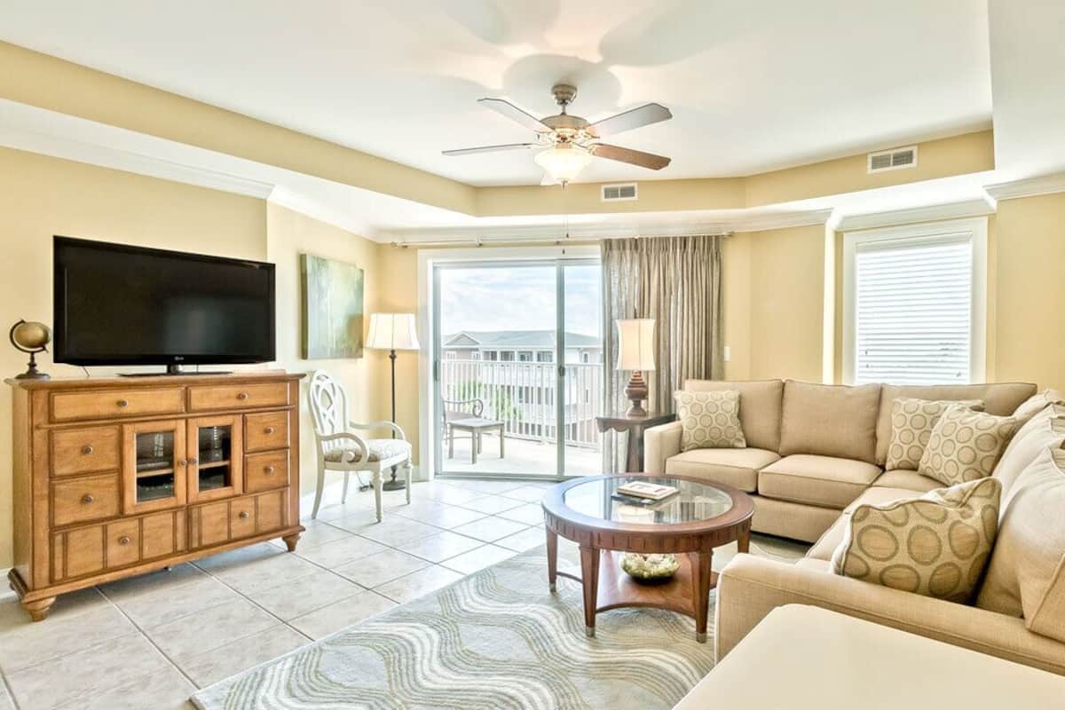 A living room with a television, sofa, coffee table, and a ceiling fan.