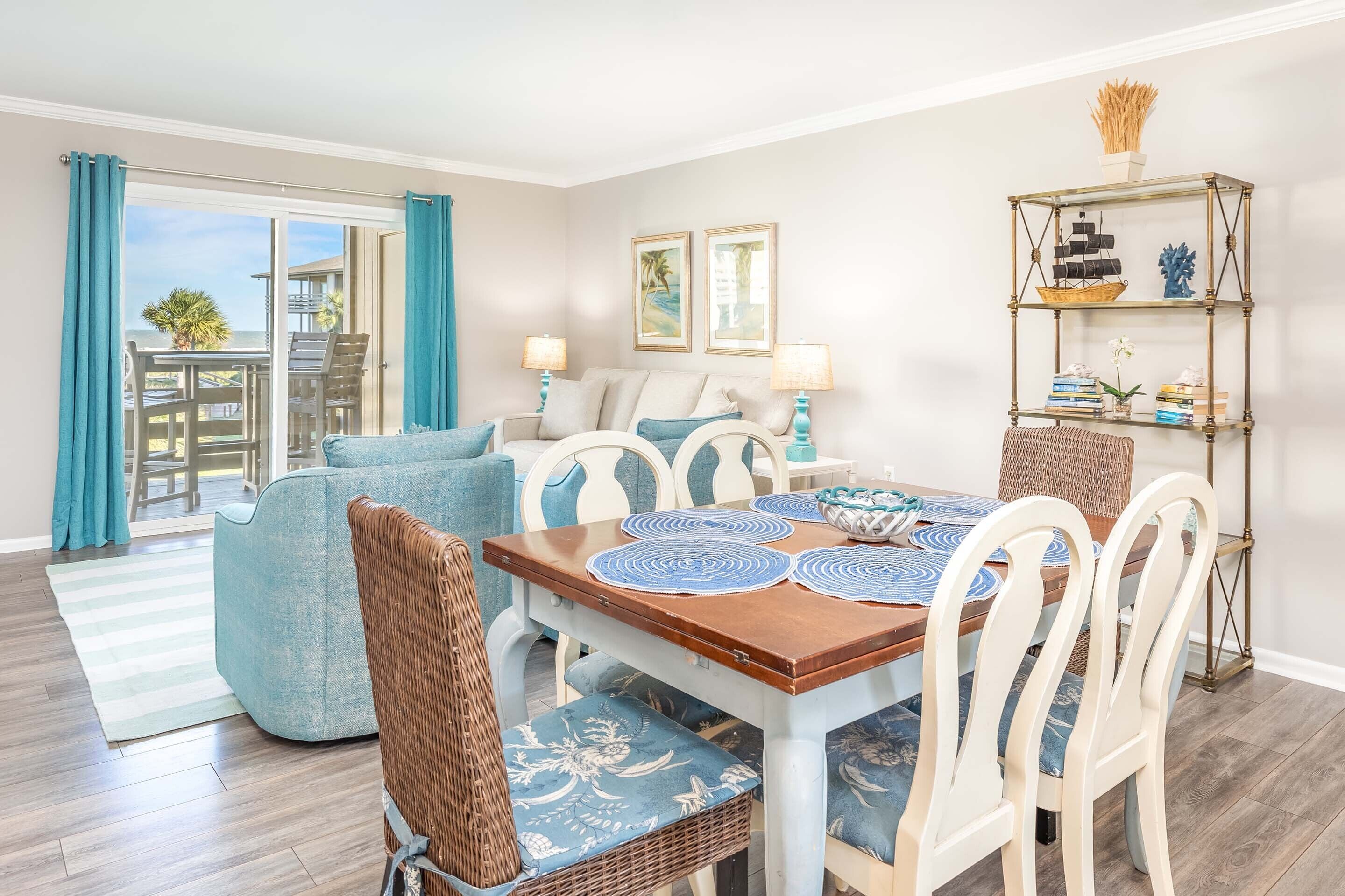 Un espace repas avec une table en bois, des chaises blanches et un tapis aux motifs bleus et blancs.