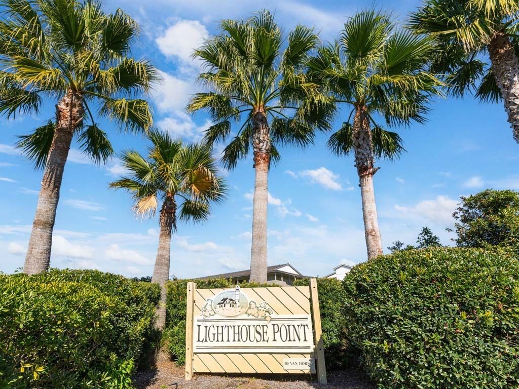 A sign for 'Lighthouse Point' with palm trees and a clear sky in the background.