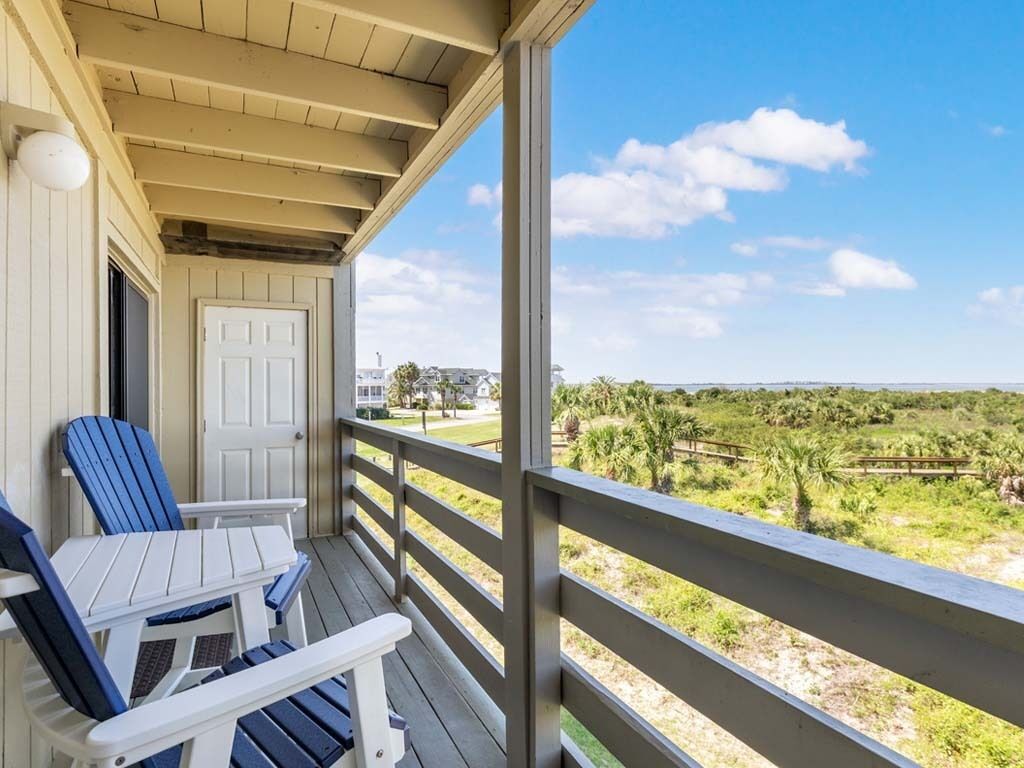 Une véranda abritée avec deux fauteuils Adirondack et une vue sur un paysage verdoyant.