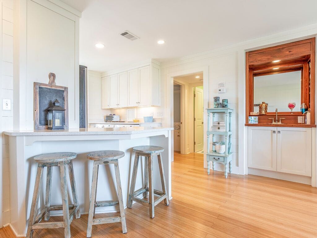 Una cucina con mobili bianchi, un'isola in legno con sgabelli e un armadietto blu con oggetti decorativi.