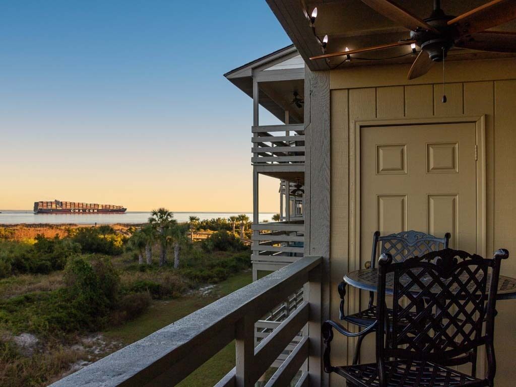 A balcony with a view of the ocean and a distant ship.