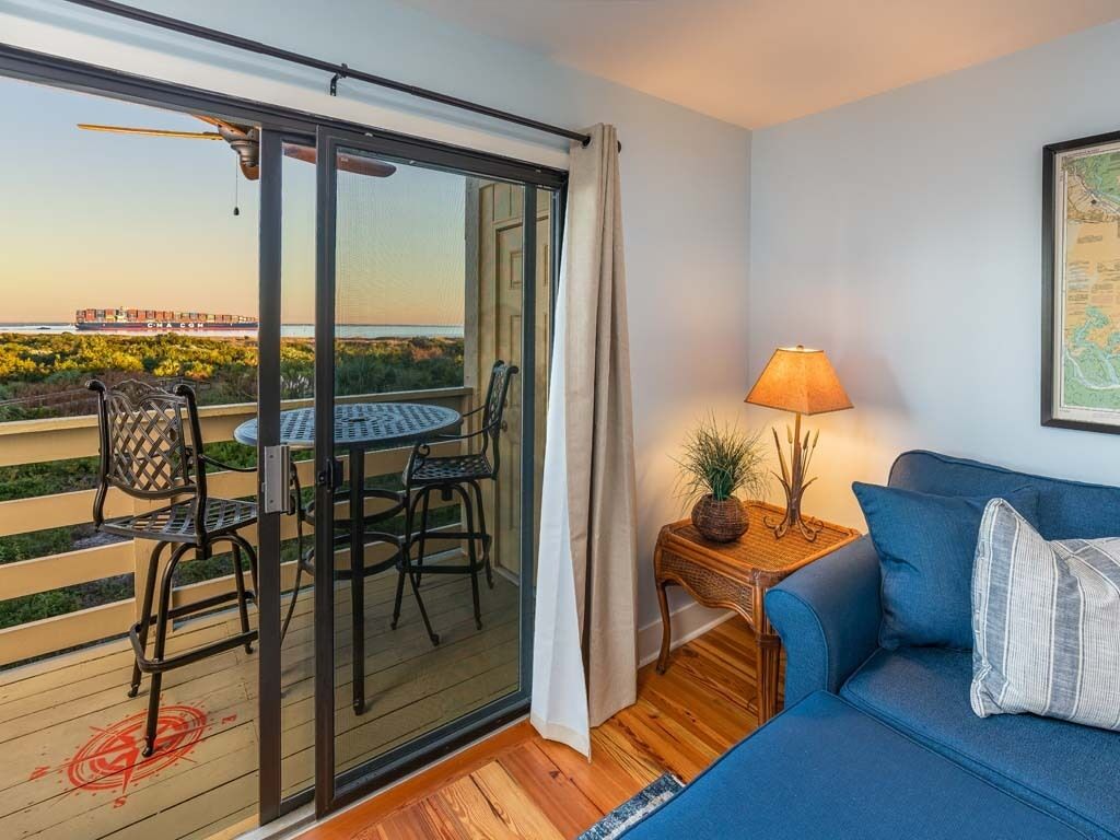 A balcony with a table and chairs, a sofa, a lamp, and a map on the wall.