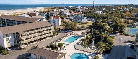 A hotel with a swimming pool, parking area, and beachfront view.