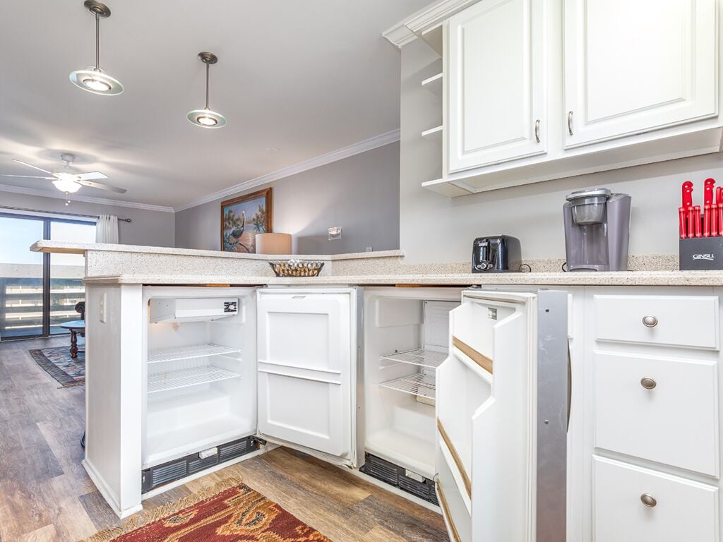 A modern kitchen with white cabinetry, a built-in coffee maker, and a set of red knives on the counter.