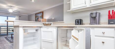 A modern kitchen with white cabinetry, a built-in coffee maker, and a set of red knives on the counter.