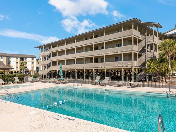 A hotel with a pool area, multiple balconies, and a covered seating area. - Lighthouse Point 1 by Tybee Vacation Rentals (Tybee Island)