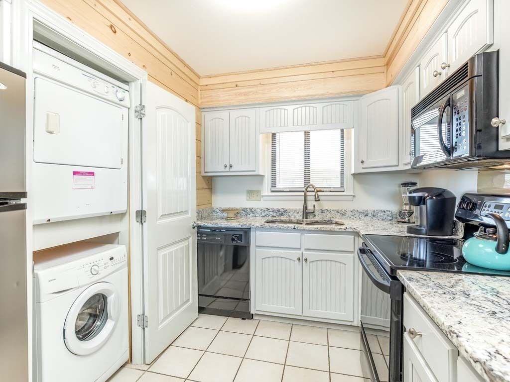 A compact kitchen with white cabinetry, a built-in oven, a microwave, and a dishwasher.