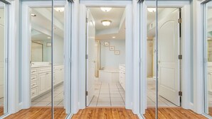 Un pasillo con puertas de cristal que dan a un baño y una zona de cocina.