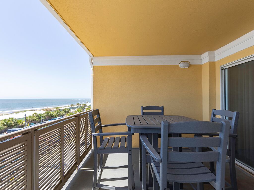 Un balcon avec une table et des chaises, donnant sur une plage.