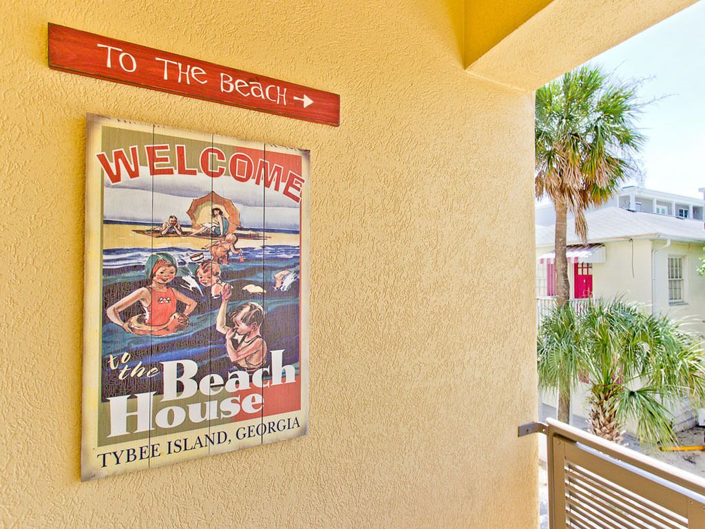 Ein Willkommensschild für das Beach House auf Tybee Island, Georgia, mit einem Hinweisschild darüber.