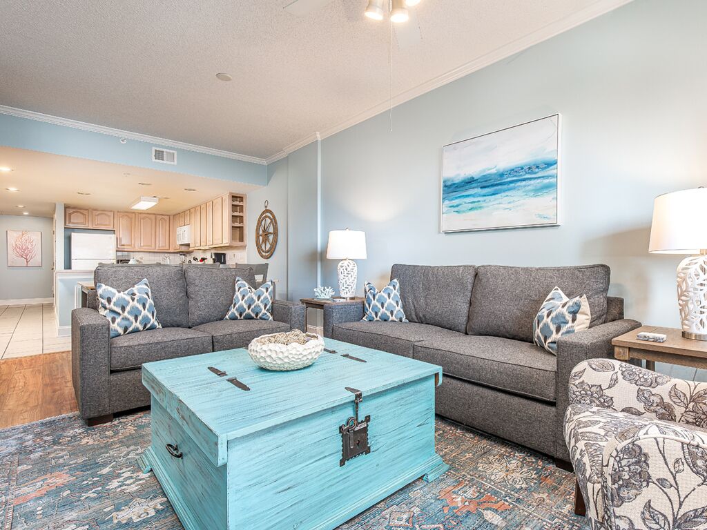 A living room with two gray sofas, a turquoise coffee table, and a patterned rug.