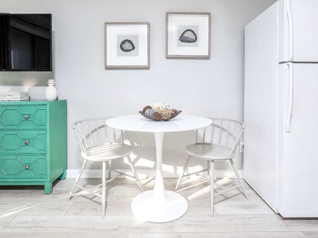 A kitchen with a white table and chairs, a green cabinet, and a white refrigerator.