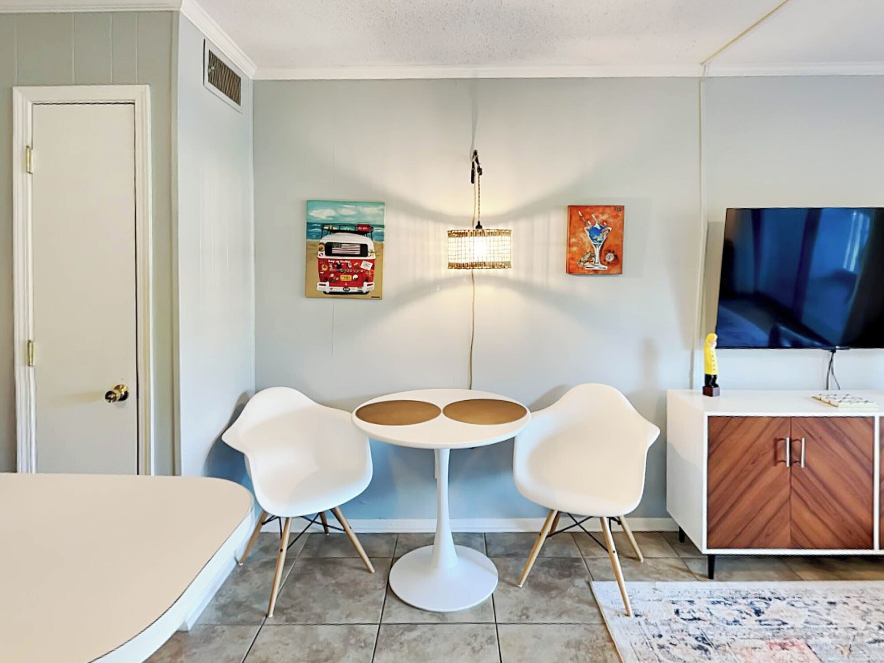 Una sala de estar moderna con un sofá blanco, una mesa redonda y un televisor sobre un mueble de madera.