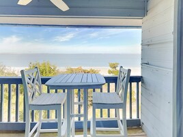 Un espace extérieur abrité, équipé d’une table et de deux chaises, donnant sur une plage.