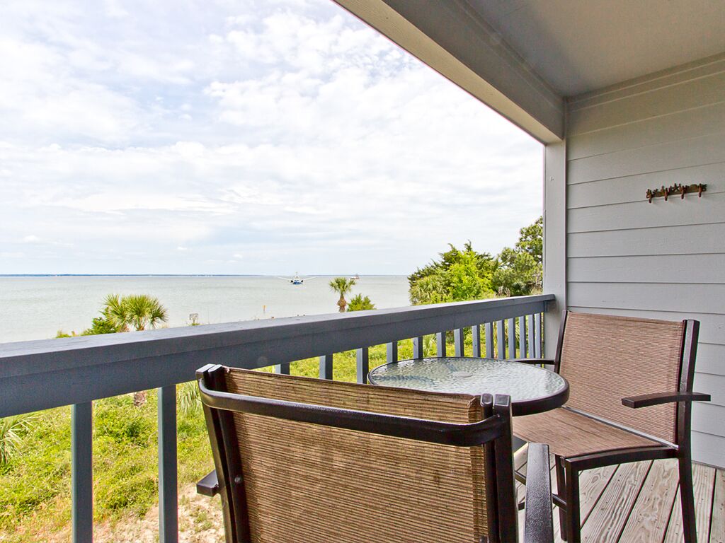 Ein Balkon mit Blick auf das Meer, zwei Korbstühle und ein kleiner Tisch.
