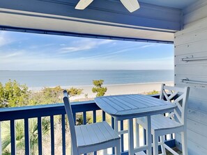 A balcony with a table and chairs overlooking a beach. - Savannah Beach Racquet Club by Tybee Vacation Rentals (Tybee Island)