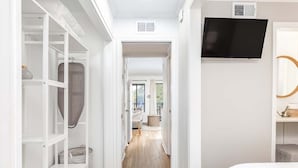 A bedroom with a bed, a TV mounted on the wall, and a walk-in closet with shelves and a hanging bag. - Savannah Beach Racquet Club by Tybee Vacation Rentals (Tybee Island)