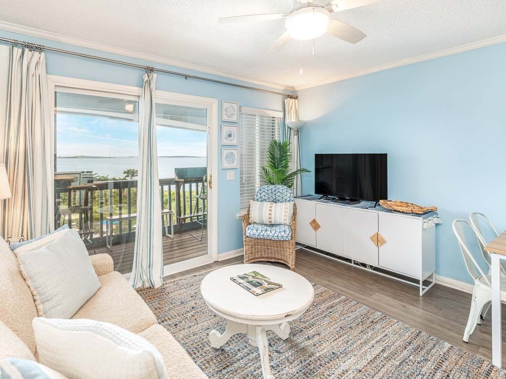 A living room with a sofa, a small table, a TV, and a balcony with a view.