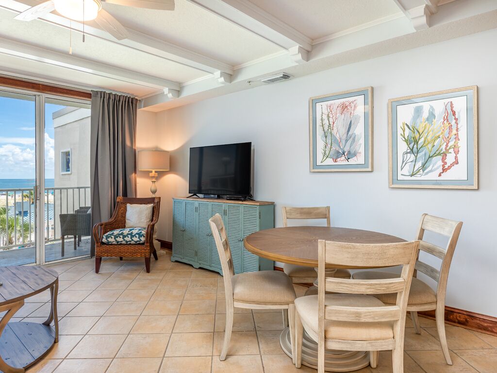 A dining area with a round table and chairs, a television on a cabinet, and artwork on the wall.