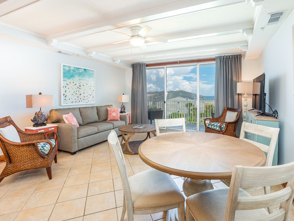 Un salon spacieux avec une grande table ronde, des sièges confortables, un canapé et un balcon avec vue.