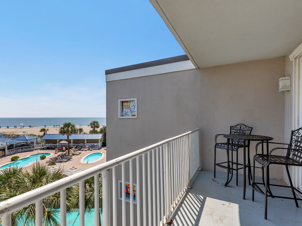 Een balkon met uitzicht op een strand en een zwembad.