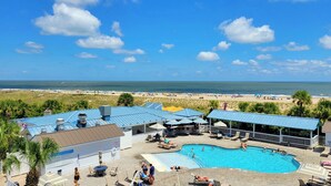 A resort with a swimming pool, beach view, and outdoor seating areas. - The Vue by Tybee Vacation Rentals (Tybee Island)