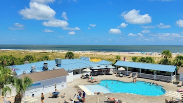 A resort with a swimming pool, beach view, and outdoor seating areas.