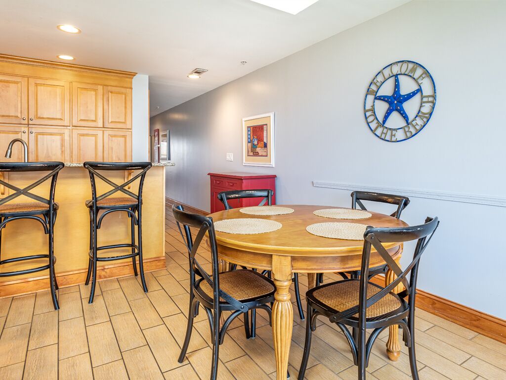 A dining area with a wooden table and chairs, a red cabinet, and a wall clock.