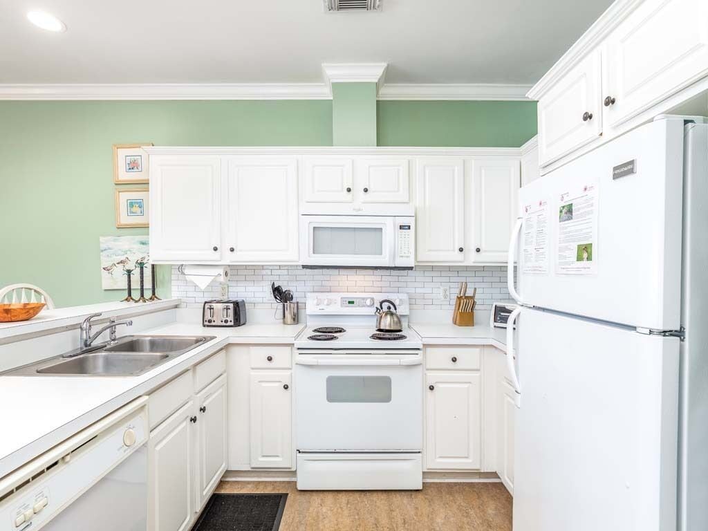 A kitchen with white cabinets, a microwave, a stove, and a refrigerator.