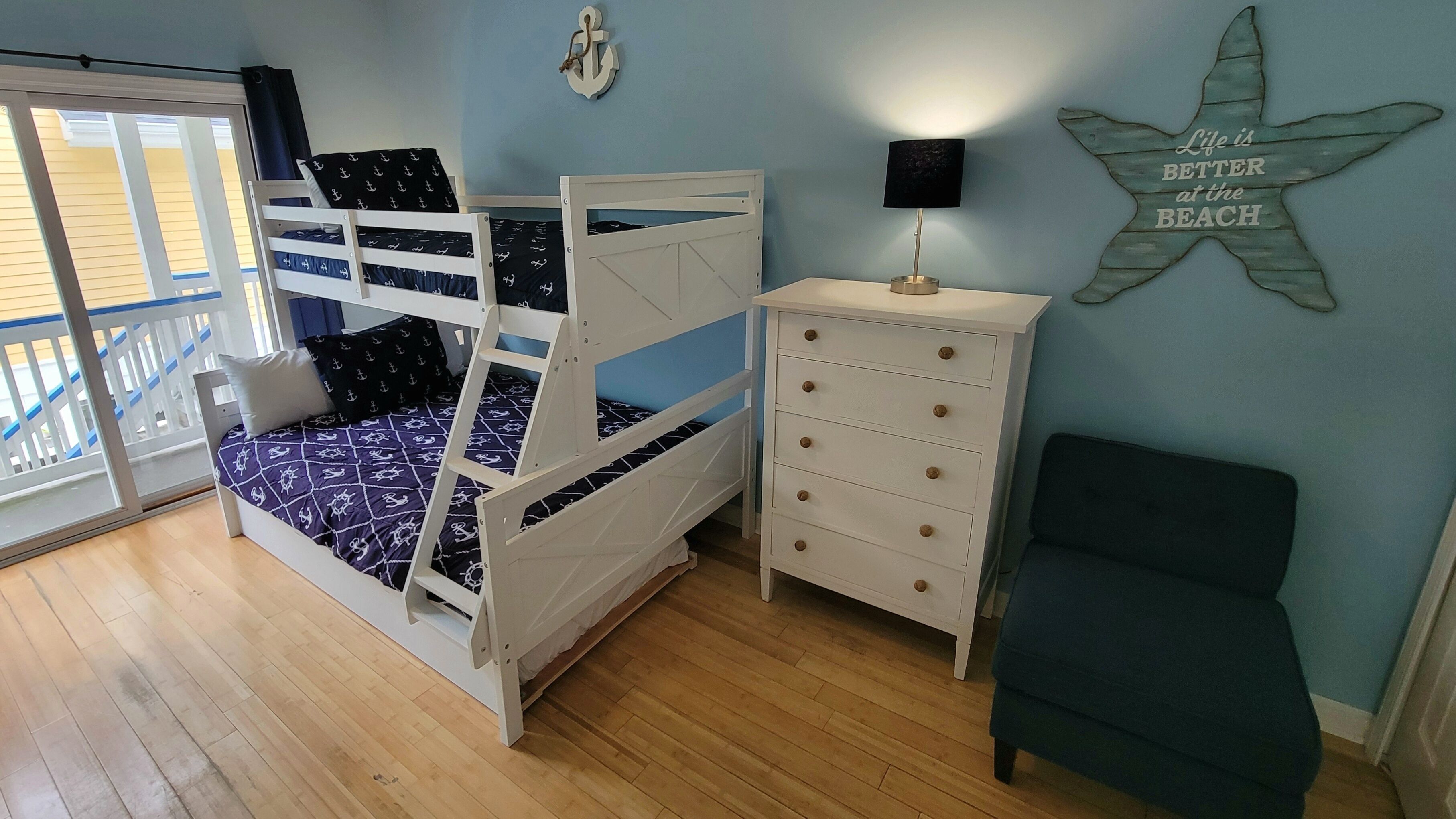 A room with a bunk bed, a dresser, a chair, and a starfish decoration on the wall.