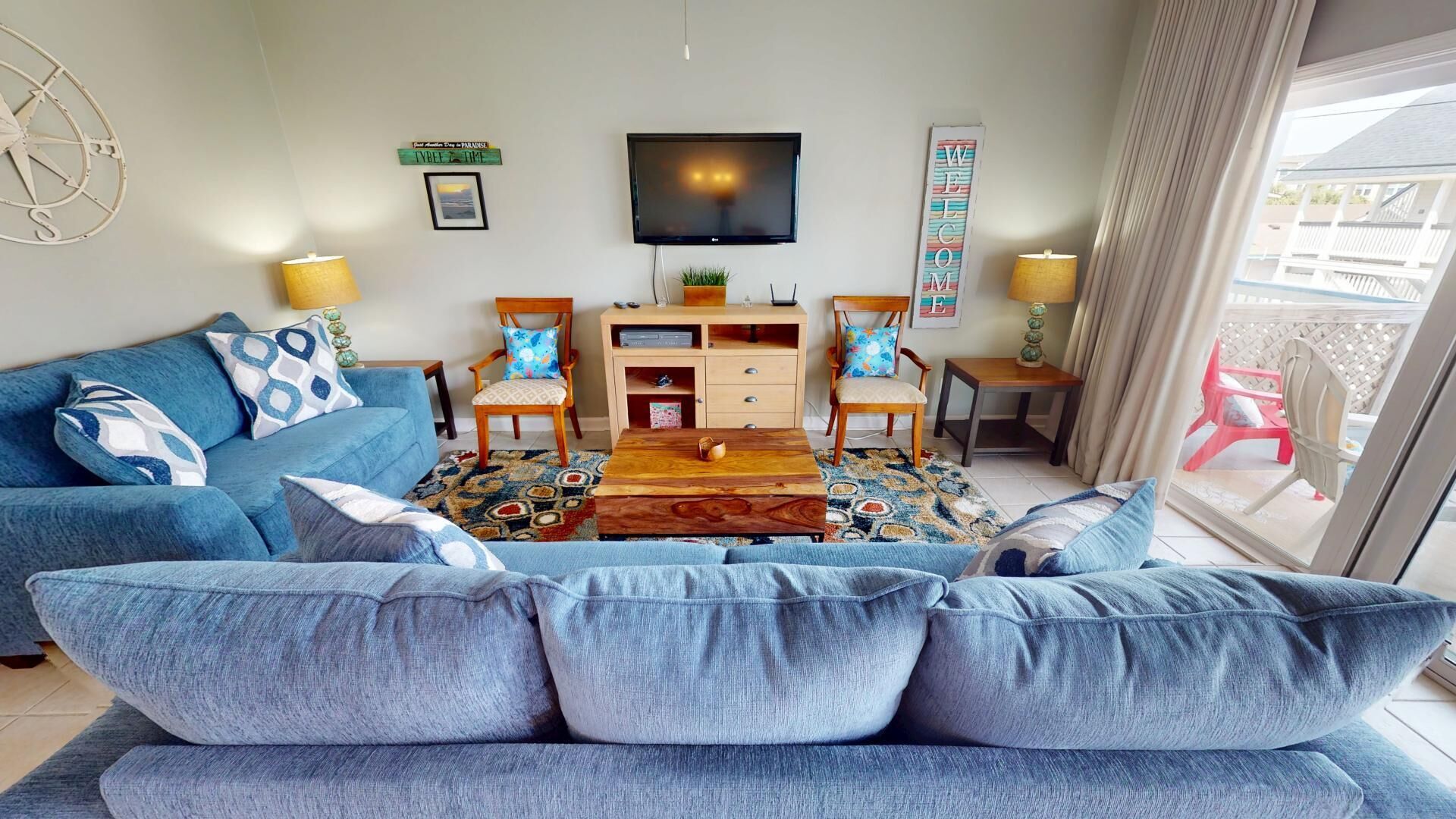 Una sala de estar con un sofá azul, una mesa de centro y un televisor en la pared.
