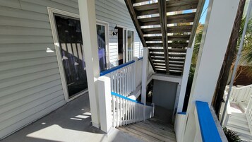 A covered outdoor staircase with a white railing and a wooden deck above.