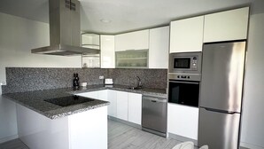 A modern kitchen with white cabinetry, granite countertops, stainless steel appliances, and a built-in oven. - PUSHE Village Playa Granada Beach & Golf 3 (Motril)