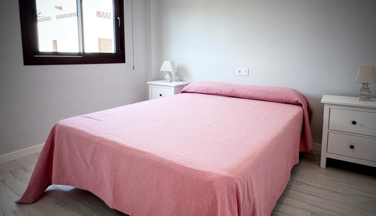 A bedroom with a bed, nightstands, and a window.