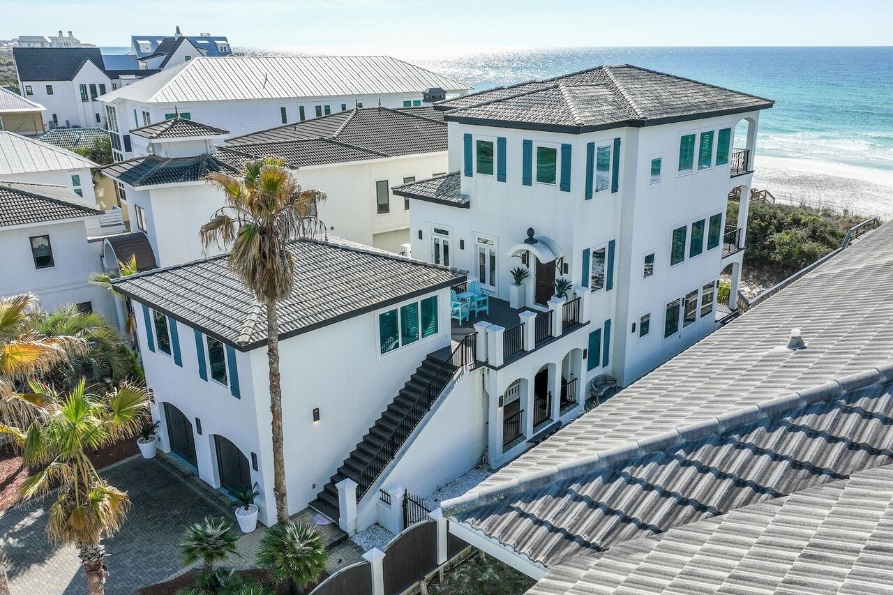 A coastal residential building with multiple levels, a staircase, and a view of the beach.