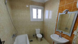 A bathroom with a bathtub, toilet, and sink. - Marseilia Land (El Alamein)