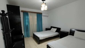 A hotel room with a large bed, a smaller bed, a desk, and a wardrobe. - Marseilia Land (El Alamein)