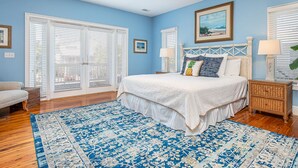 A bedroom with a large bed, a ceiling fan, and a view through the window blinds. - 5 Oclock Somewhere by Tybee Vacation Rentals (Tybee Island)