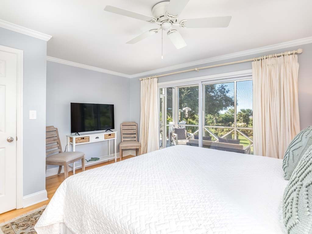 A bedroom with a bed, a television, a desk, and a chair.