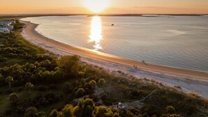 Un paysage côtier avec une plage, un petit bateau et quelques personnes se promenant le long du rivage.