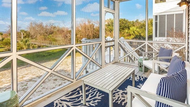 Un espace extérieur abrité doté d’une terrasse en bois, de rampes blanches et offrant une vue sur le paysage environnant.