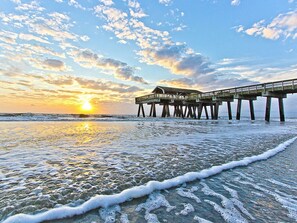 A pier extending into the ocean with a sunset in the background.